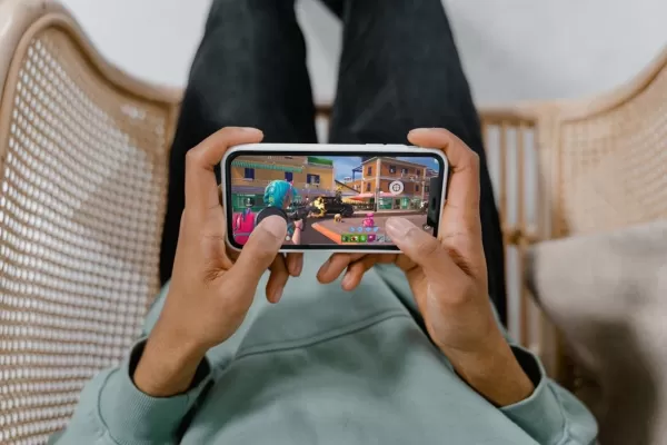 Un paio di mani che tiene un telefono che gioca a Fortnite con un grilletto magnetico collegato al telefono